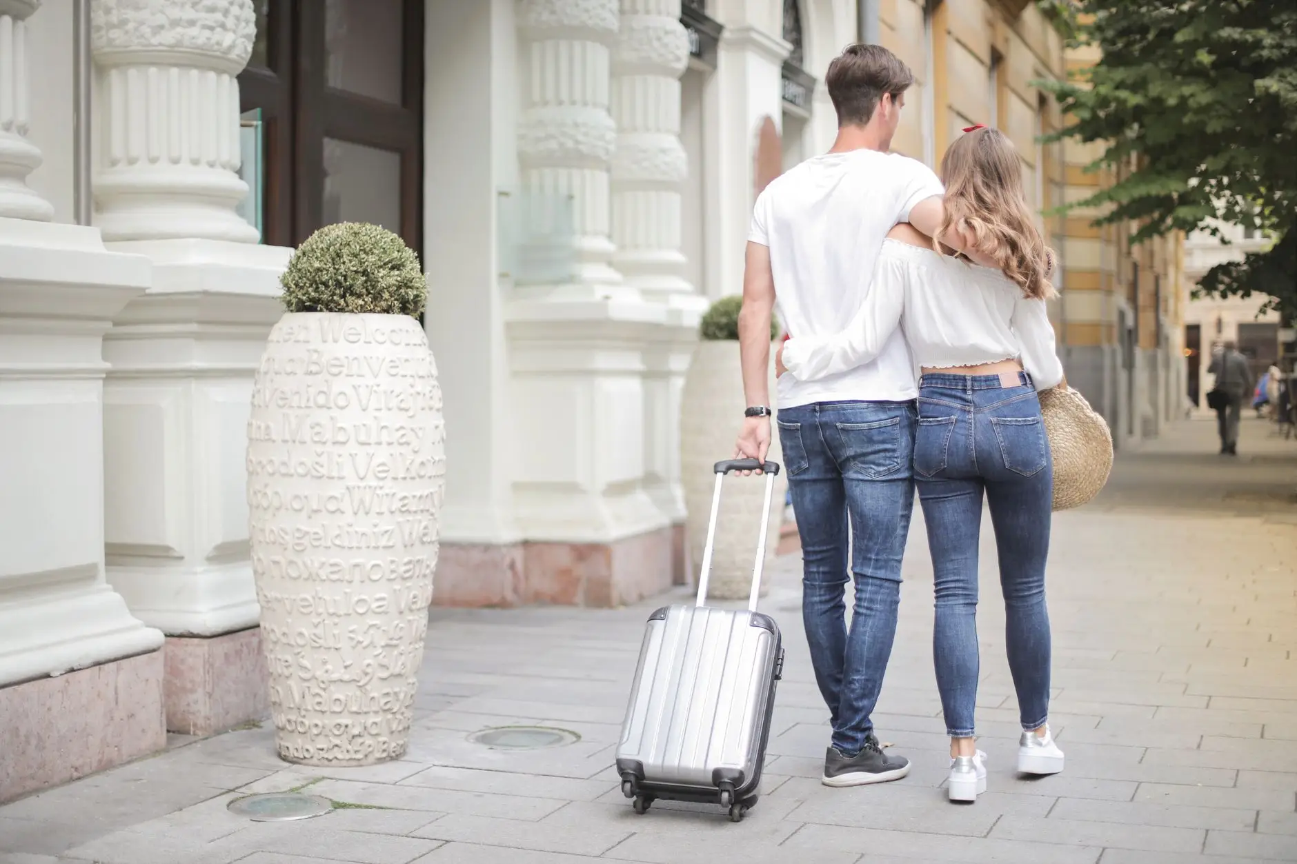 pareja-de-espaldas-caminando-con-su-maleta-al-empezar-un-viaje Bikote bat bizkarrez, maletarekin oinez, eztei-bidaia hastean