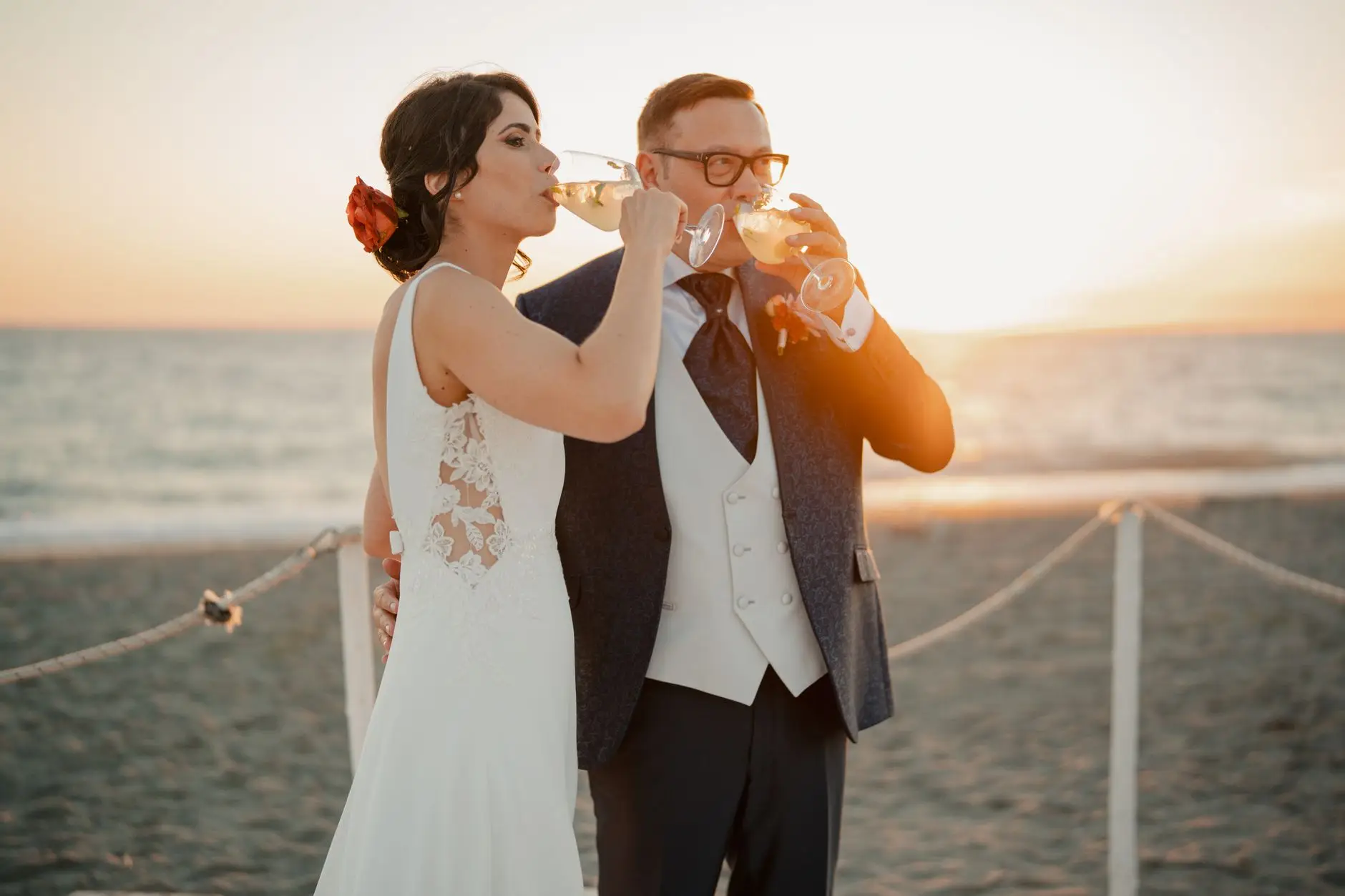 Pareja de recién casados brindando con champán al atardecer en la playa