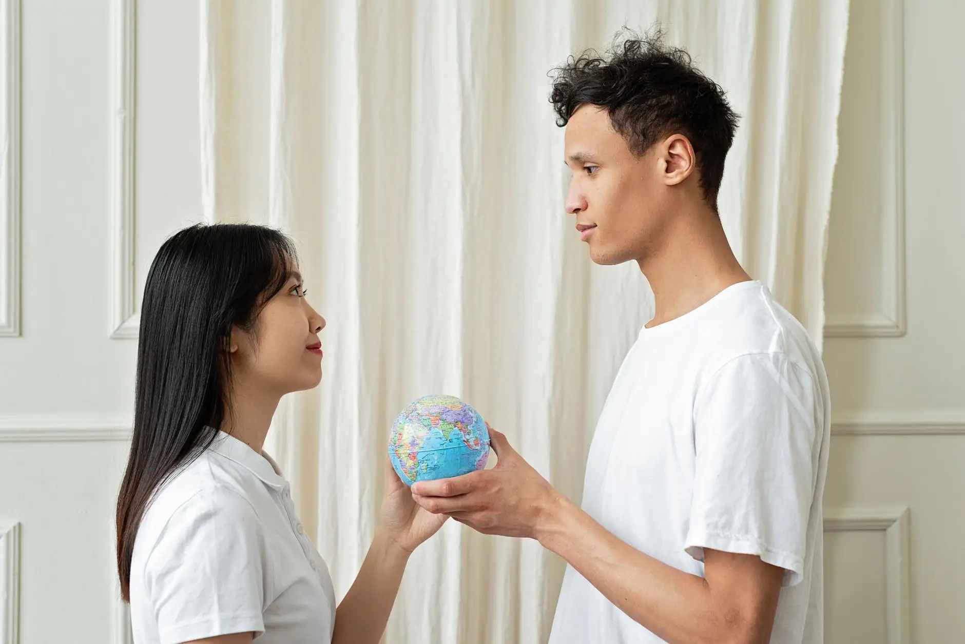Pareja sosteniendo un pequeño globo terráqueo mientras decide el destino de su viaje de novios