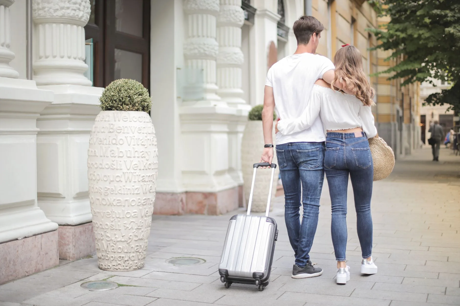 Pareja de espaldas caminando con su maleta al empezar un viaje
