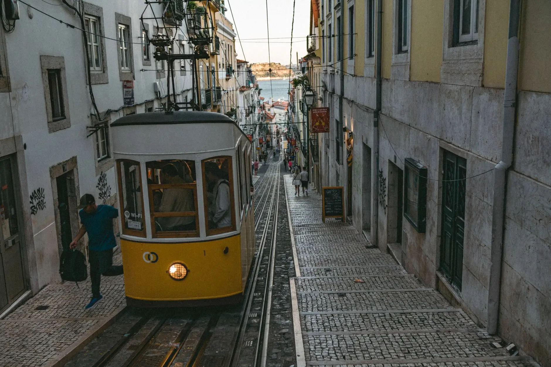 Tranvía amarillo de Lisboa subiendo por el barrio de Alfama al atardecer