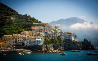 Amalfi herria terrazen eta mendien artean, itsasoaren ondoan Amalfiko etxeak mailaka portuaren gainean, mendiak lainopean, Amalfiko kostaldean