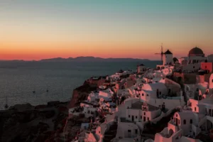 Casas blancas y molino de Oía en Santorini al atardecer, con el mar Egeo al fondo