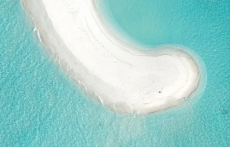 Harea zuriko bankua ur turkesen artean, Maldivetan Harea zuriko banku kurbatu baten airetiko ikuspegia, ur turkesez inguratuta, Maldivetan