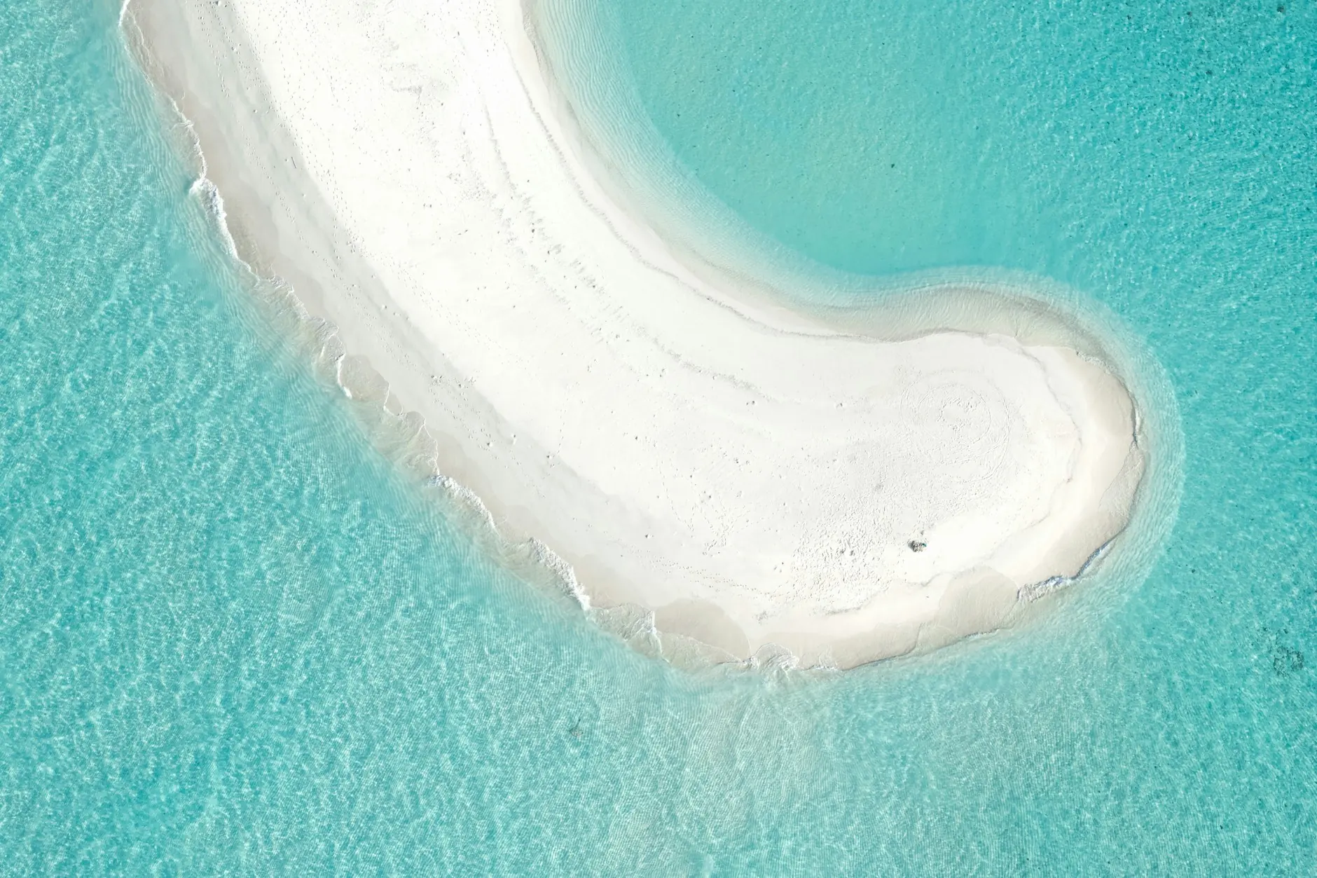 Vista aérea de un banco de arena blanca en forma de curva rodeado de aguas turquesas en Maldivas