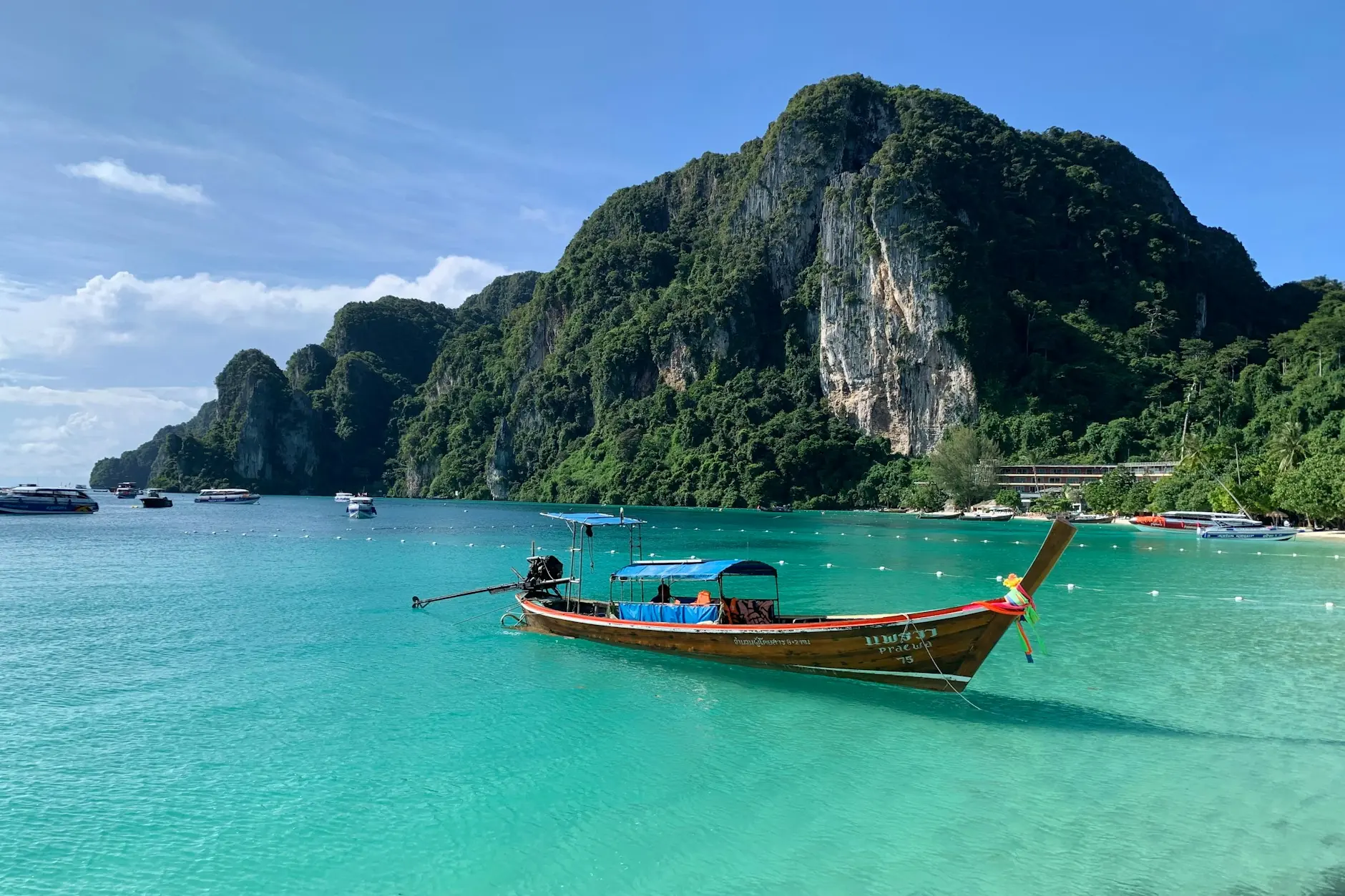 Barca tailandesa de cola larga sobre aguas turquesas frente a acantilados de Koh Phi Phi, Tailandia