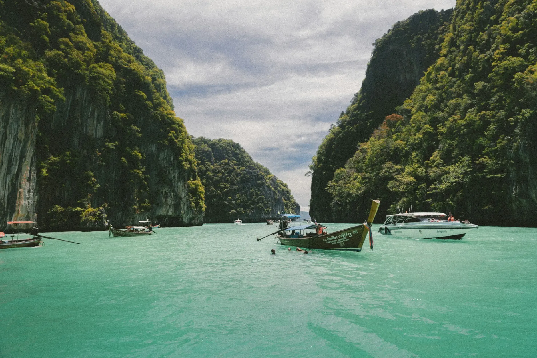 Buztan luzeko txalupa tradizionalak itsaslabar berdeen artean, Phi Phi uharteetan (Thailandia)