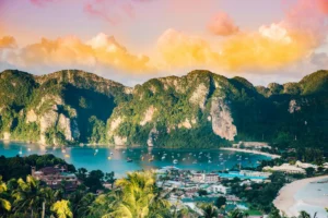 Barcas en una bahía de Phi Phi rodeada de montañas verdes al amanecer, en Tailandia