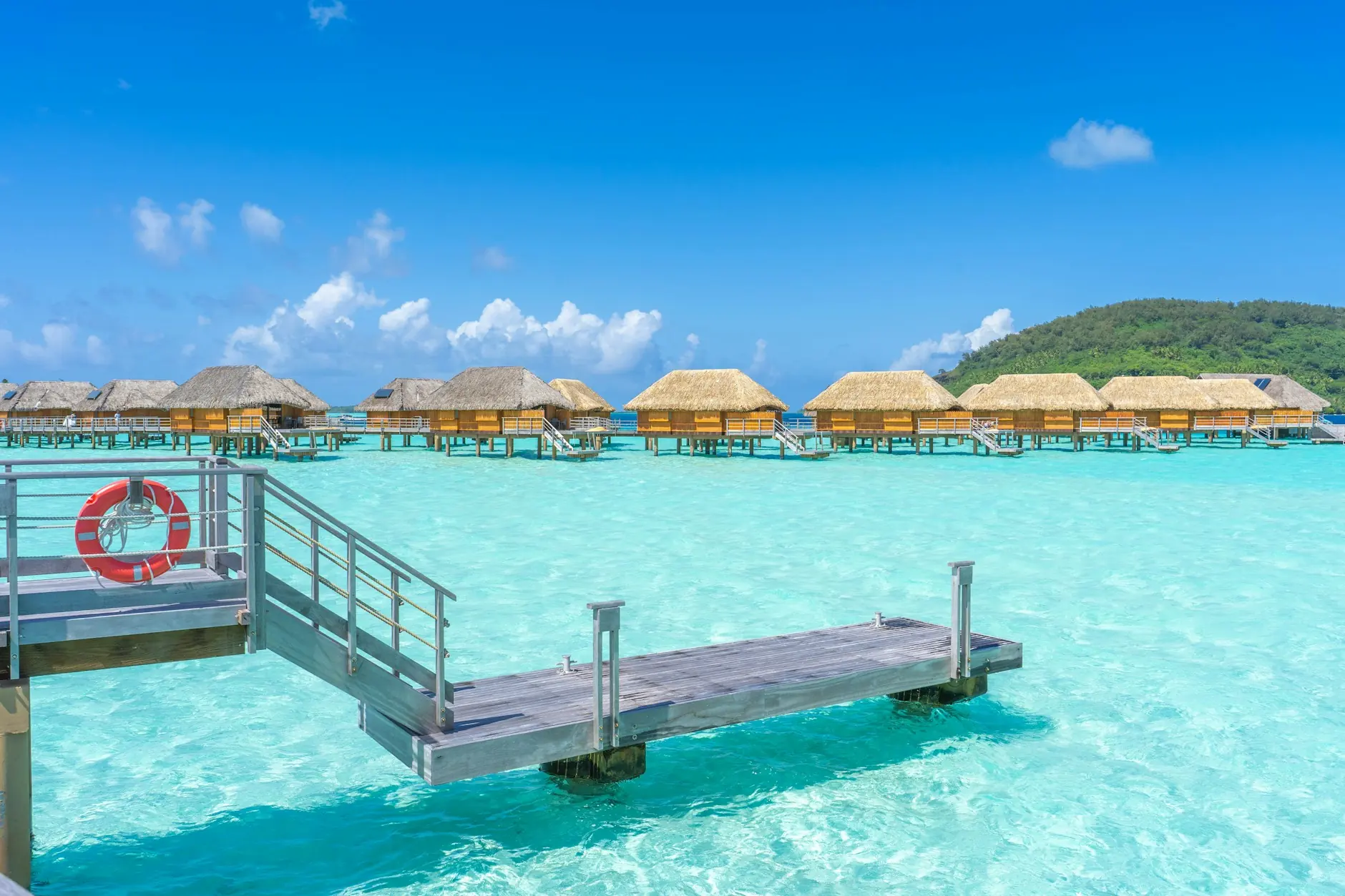 Bungalós sobre pilotes con techo de paja en la laguna turquesa de Bora Bora, Polinesia Francesa