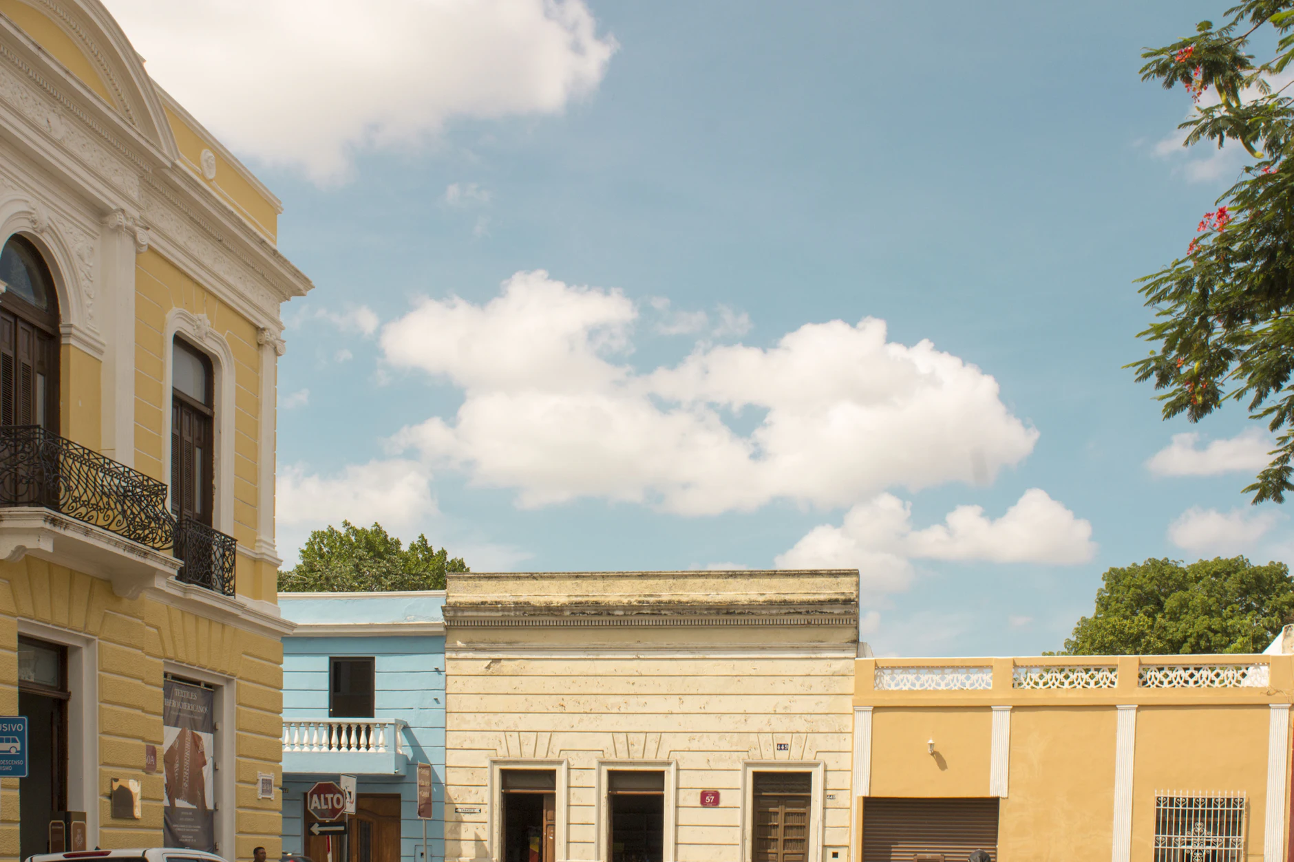 Calle del centro histórico de Mérida con fachadas coloniales amarillas y azules bajo cielo azul