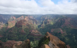 Waimea arroilaren horma gorrixka eta berdeak hodei zuriko zeru baten azpian, Kauain, Hawaiin