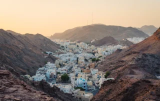 Etxe zuriak mendi harritsuen artean, Maskatetik gertu, Oman Etxe zurietako herria mendi idorren artean Maskatetik gertu, Omanen, ilunabarreko argi epelarekin
