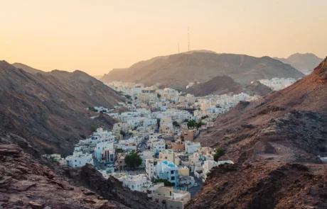 Etxe zuriak mendi harritsuen artean, Maskatetik gertu, Oman Etxe zurietako herria mendi idorren artean Maskatetik gertu, Omanen, ilunabarreko argi epelarekin