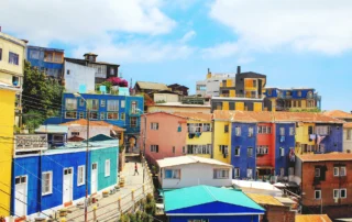 Kolore biziko etxe mailakatuak Valparaisoko muinoetan, zeru urdinaren azpian