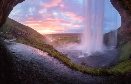 Cascada de Seljalandsfoss vista desde detrás al atardecer, Islandia Cascada de Seljalandsfoss vista desde la cueva de detrás con cielo rosado al atardecer en Islandia