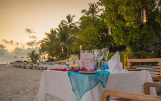 Cena romántica en la playa al atardecer en Maldivas Mesa para cena romántica con pétalos y farolillos sobre la arena al atardecer en Maldivas