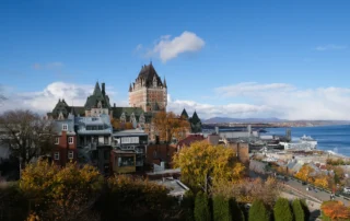 Quebec hiria udazkeneko zuhaitzen artean San Lorentzoren ondoan Quebec hiri zaharreko teilatuak udazkeneko koloreko zuhaitzen artean, San Lorentzo ibaiaren ondoan