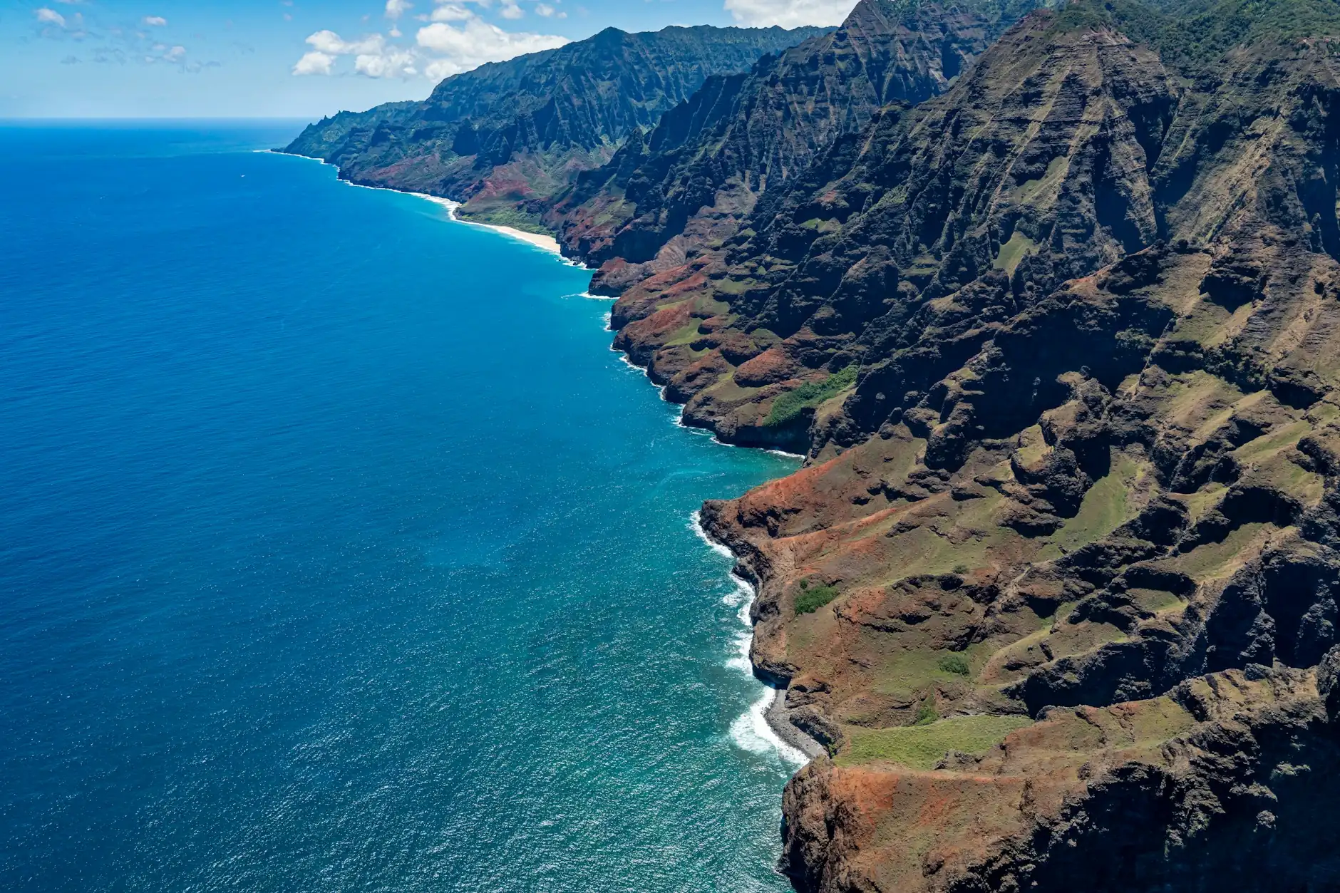 Na Pali kostaldeko itsaslabar berdeen aireko ikuspegia ozeano turkesaren gainean, Kauain (Hawaii)