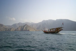 Un dhow omaní de madera navega por las aguas tranquilas de los fiordos de Musandam, en Omán
