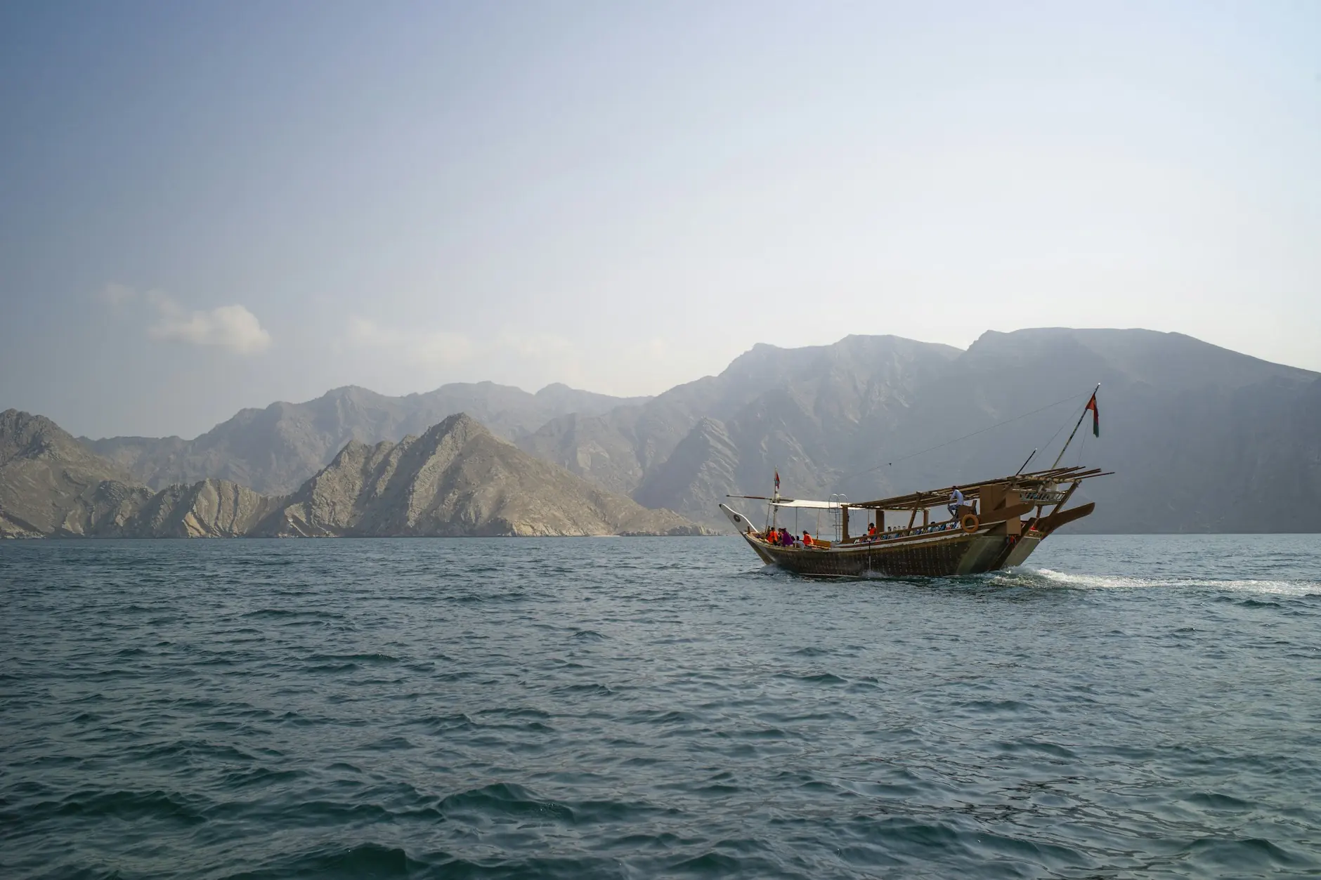 Un dhow omaní de madera navega por las aguas tranquilas de los fiordos de Musandam, en Omán