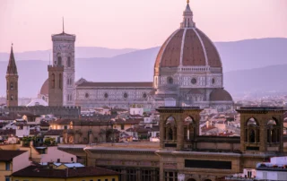 Florentziako Duomoaren kupula ilunabarrean teilatuen gainean Brunelleschiren kupula eta Florentziako Duomoaren kanpandorrea, ilunabarreko zeru malba kolorekoarekin