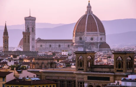 Florentziako Duomoaren kupula ilunabarrean teilatuen gainean Brunelleschiren kupula eta Florentziako Duomoaren kanpandorrea, ilunabarreko zeru malba kolorekoarekin