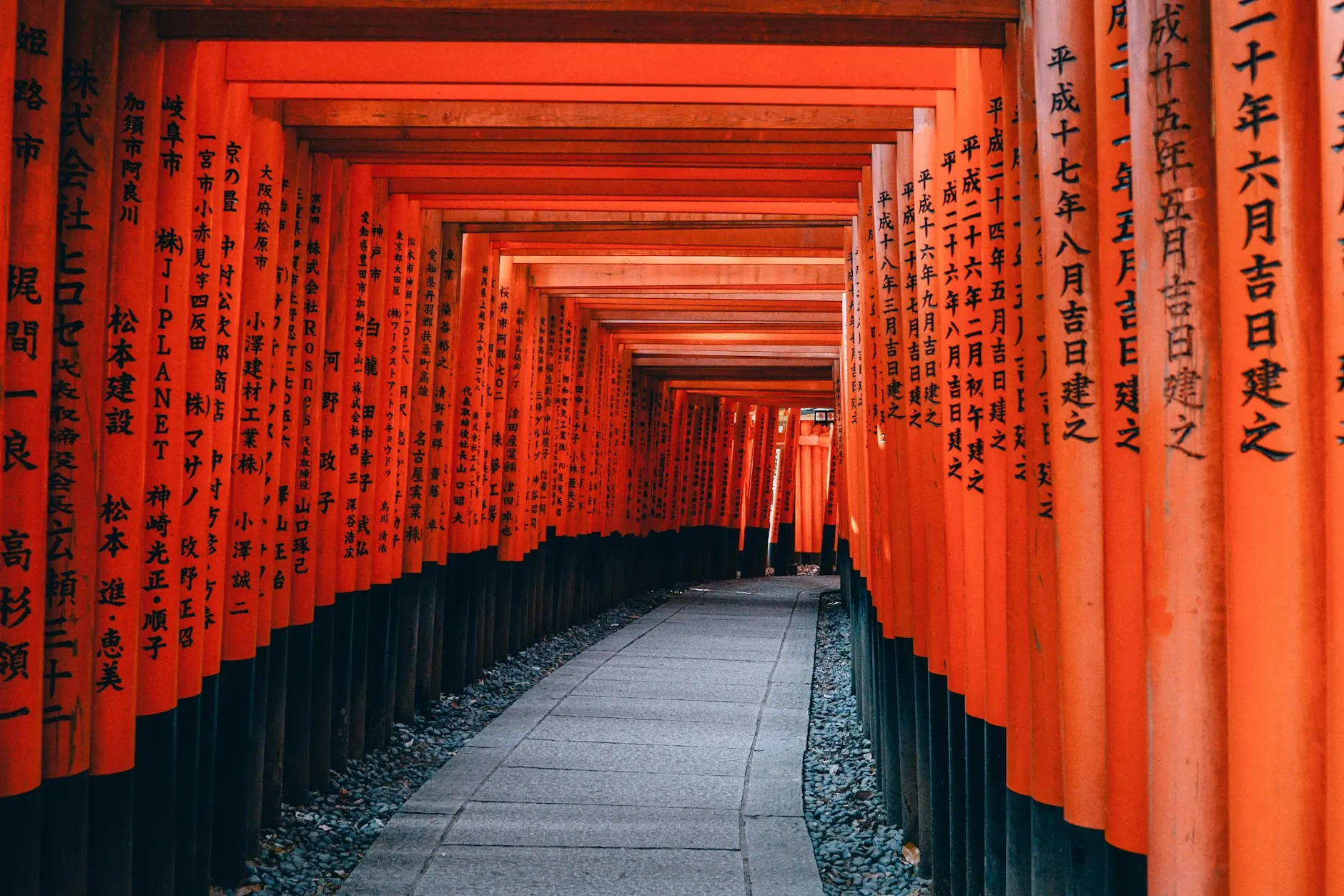 Sendero de piedra bajo el túnel de torii bermellón del santuario Fushimi Inari en Kioto