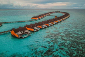 Uraren gaineko villen ilara kurbatua goitik ikusita, arrezifearen ondoan, Maldivetan