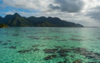 Laguna cristalina y montañas volcánicas verdes de Moorea Aguas turquesas sobre el arrecife de coral de Moorea con sus picos volcánicos verdes al fondo