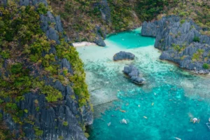Vista aérea de una laguna turquesa rodeada de farallones de piedra caliza en El Nido, Palawan