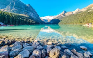 Lake Louiseko ur turkesak mendi eta baso artean Lake Louiseko harri-ertza eta ur turkesak, mendiz inguratuta, Banffen, Kanadan