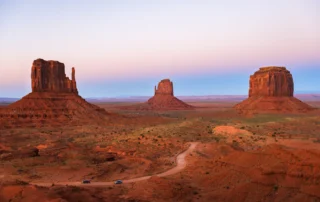 Monument Valleyko Mittens egunsentian, Utah eta Arizona artean Monument Valleyko Mittens harkaitz gorrixkak, basamortuan barrena doan lurrezko bide batekin