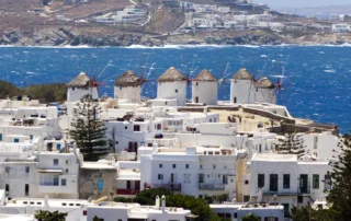Hilera de molinos de viento de Míkonos sobre casas blancas y el mar azul