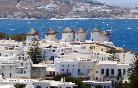Hilera de molinos de viento de Míkonos sobre casas blancas y el mar azul