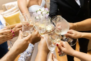 Novia vestida de blanco e invitados chocando copas de champán durante el brindis del banquete de boda