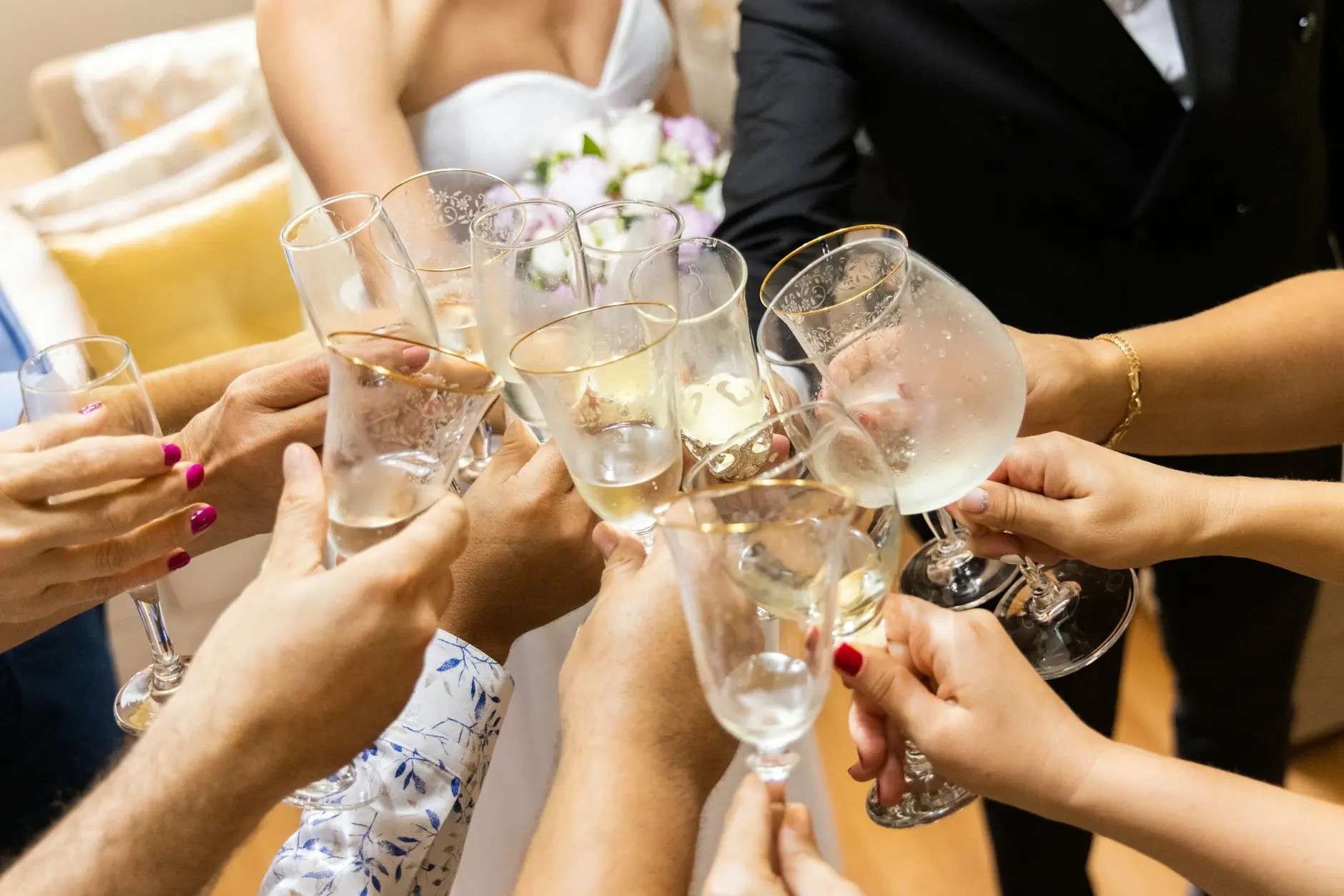 Novia vestida de blanco e invitados chocando copas de champán durante el brindis del banquete de boda