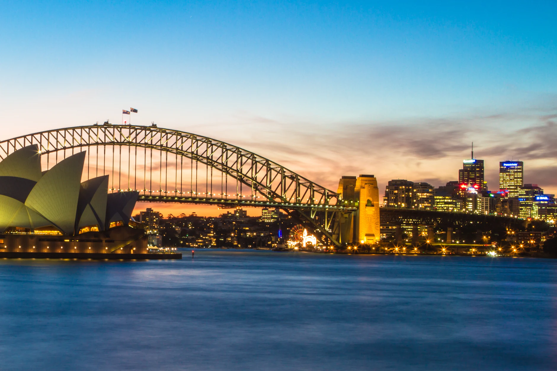Ópera de Sídney y puente de la bahía al atardecer La Ópera de Sídney y el Harbour Bridge iluminados al atardecer sobre la bahía, Australia