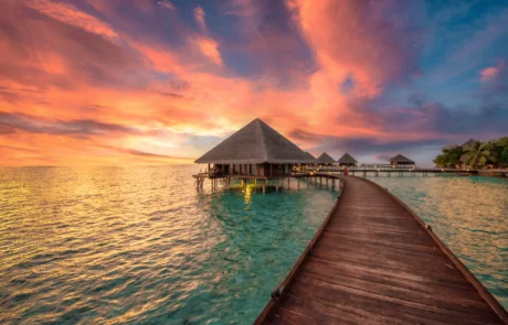 Egurrezko pasabidea ur gaineko villa batera ilunabarrean, Maldivetan Ur gaineko villa batera daraman egurrezko pasabidea ilunabarreko zeru azpian, Maldivetan