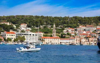 Itsasontziak Hvarko portuan, herriaren eta kanpandorrearen aurrean Txalupak Hvar uharteko portuan nabigatzen, herria eta kanpandorrea atzean dituztela