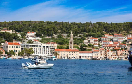 Itsasontziak Hvarko portuan, herriaren eta kanpandorrearen aurrean Txalupak Hvar uharteko portuan nabigatzen, herria eta kanpandorrea atzean dituztela
