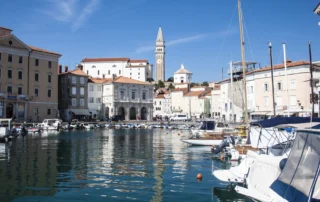 Pirango portua Done Jurgiren kanpandorrearekin, Eslovenia Itsasontziak Pirango portu txikian, fatxada veneziarrak eta Done Jurgiren kanpandorrea atzealdean