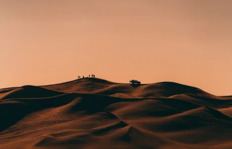 Safari por las dunas del desierto de Dubái al atardecer Siluetas de viajeros y un todoterreno sobre las dunas del desierto de Dubái al caer la tarde