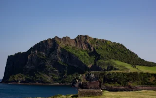 Cráter volcánico Seongsan Ilchulbong junto al mar en Jeju El cono volcánico Seongsan Ilchulbong se alza sobre la costa de la isla de Jeju en un día despejado