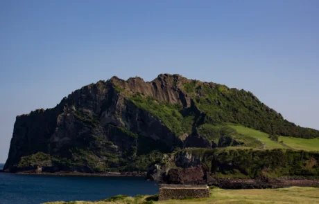 Cráter volcánico Seongsan Ilchulbong junto al mar en Jeju El cono volcánico Seongsan Ilchulbong se alza sobre la costa de la isla de Jeju en un día despejado