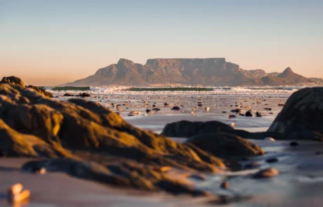 Table Mountain eta Lurmutur Hiria Bloubergstrand hondartzako harkaitzetatik ikusita, ilunabarrean