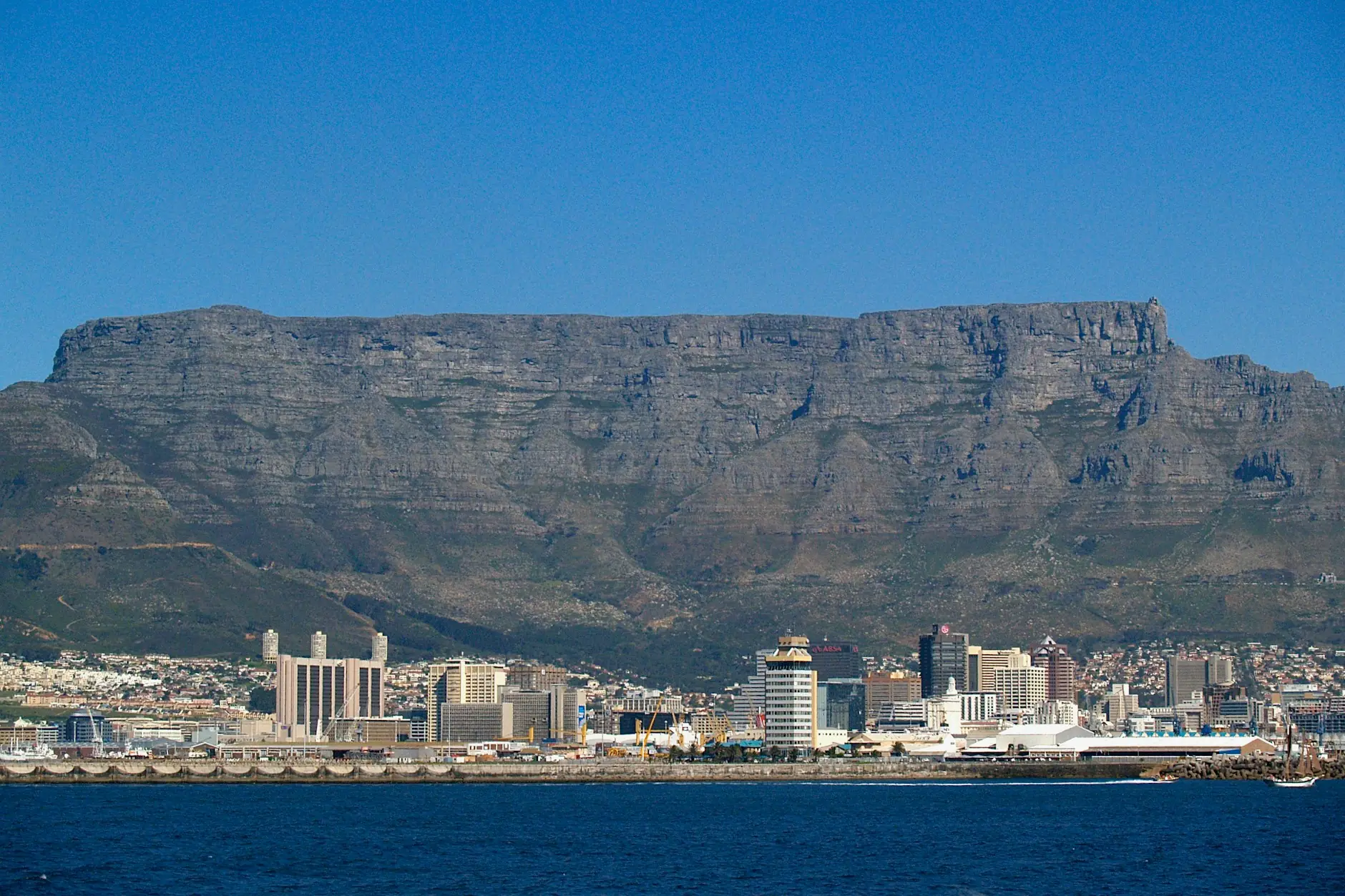 Table Mountain Lurmutur Hiriko eraikinen gainetik altxatzen da, itsasotik ikusita, zeru urdinarekin