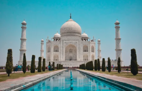 Taj Mahal de Agra con sus jardines y estanque central El Taj Mahal de Agra bajo un cielo azul despejado, con el estanque y los cipreses de sus jardines