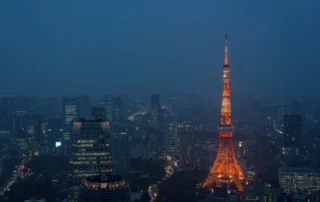 Torre de Tokio iluminada sobre el skyline nocturno Torre de Tokio iluminada en naranja sobre los rascacielos de la ciudad de noche