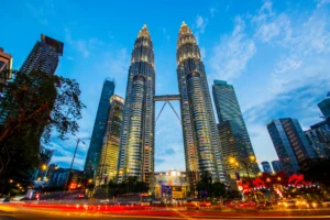 Kuala Lumpurreko Petronas dorreak argiztatuta iluntzean, trafikoaren argi-arrastoekin