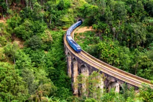 Tren azul cruzando el puente de los Nueve Arcos entre la selva verde de Ella, Sri Lanka